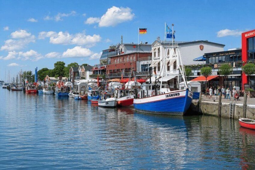 A harbor with boats docked, a blue boat named 'JASMIND,' and buildings with flags. 2