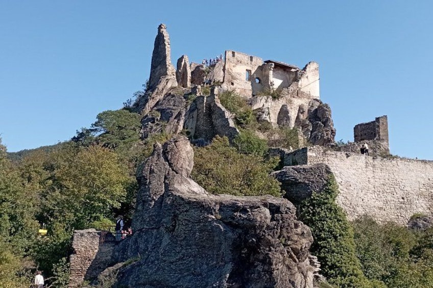 A historic castle on a rocky hill with ruins and greenery. 2