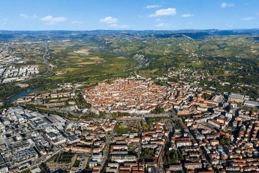 An aerial view of a city with a dense urban center, surrounded by green fields and a river. 2