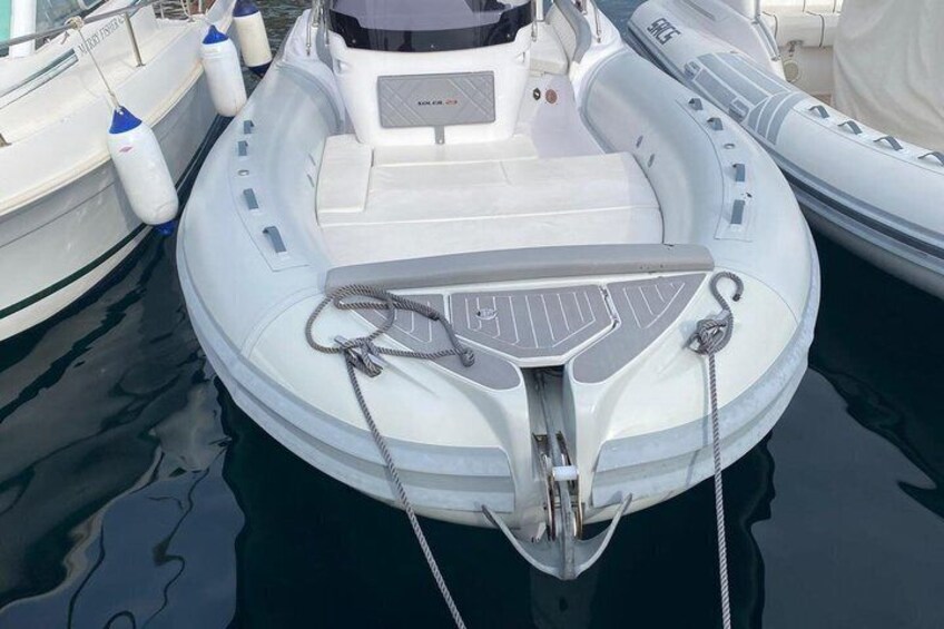 A white inflatable boat docked at a marina with a white cover and a winch on the front. 2