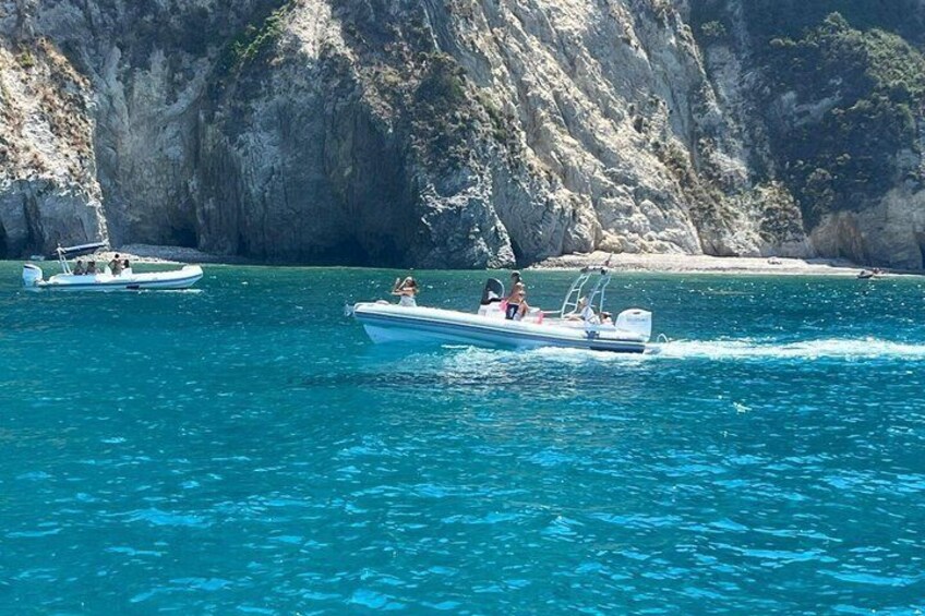 A boat on clear turquoise water with rocky cliffs in the background. 4