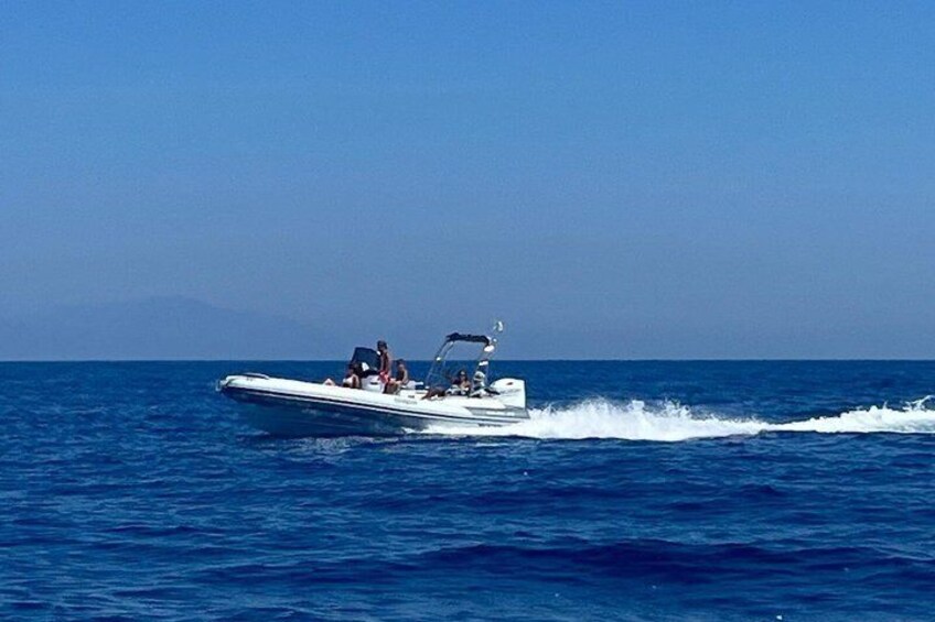 A speedboat with passengers on a clear blue sea. 5