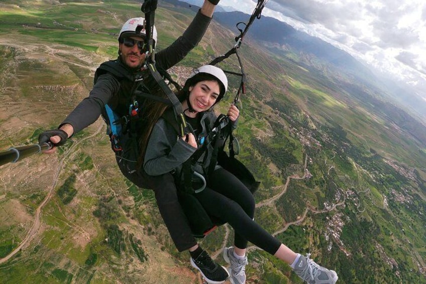 Two people skydiving with parachutes over a mountainous landscape. 1