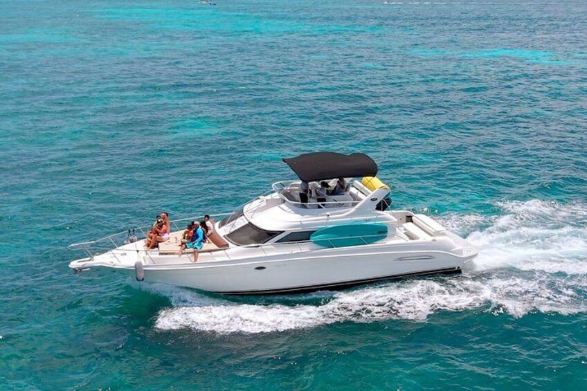 A white motorboat with a canopy, moving through turquoise water. 1