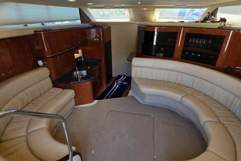 A boat interior with a curved seating area, wooden cabinetry, and a small kitchen space. 5