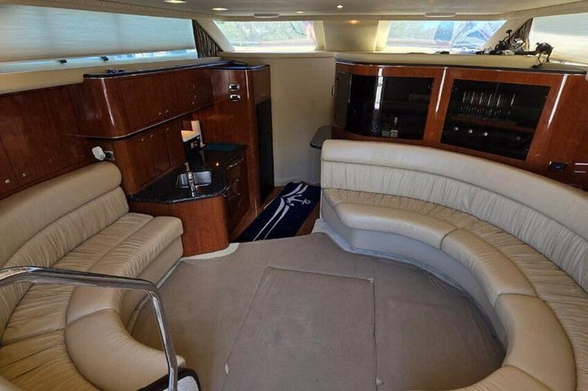 A boat interior with a curved seating area, wooden cabinetry, and a small kitchen space. 5