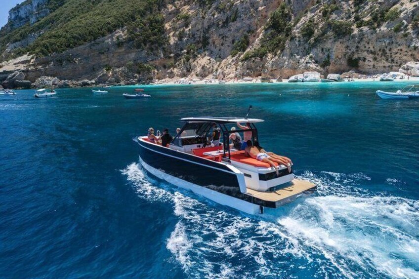 A boat on clear blue water with rocky cliffs in the background. 4