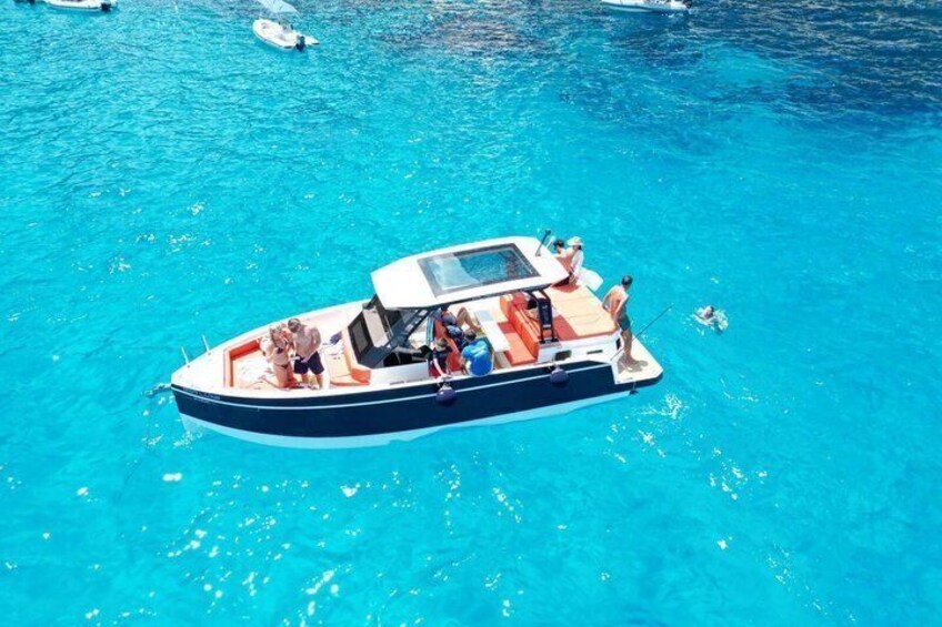 A boat with people on a clear blue sea. 5