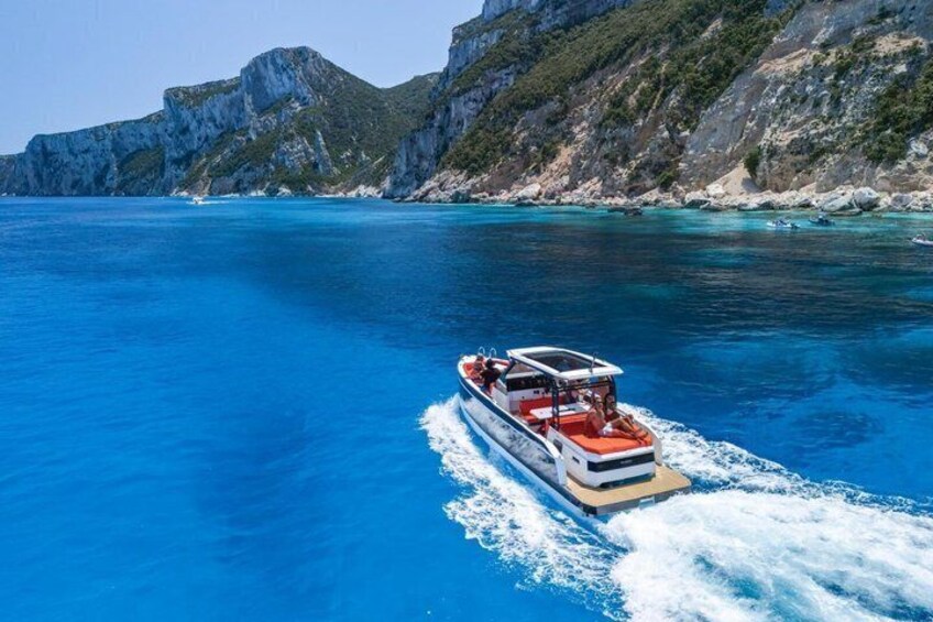A boat on a clear blue sea with rocky cliffs in the background. 3