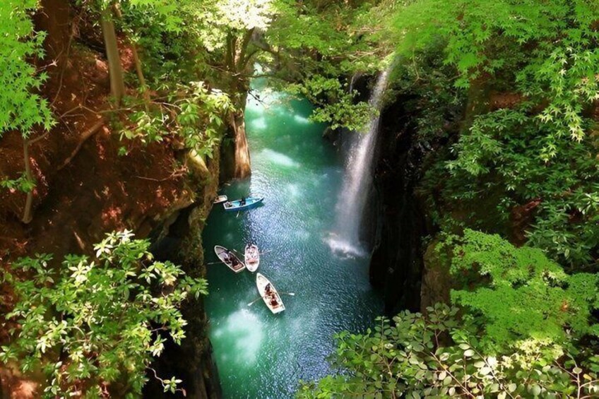 A river with kayaks, surrounded by dense forest and a waterfall. 3