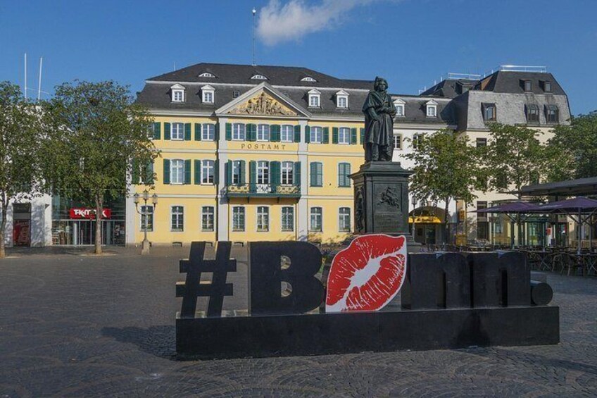 A square with a #BOND sign, a statue, and historic buildings. 5