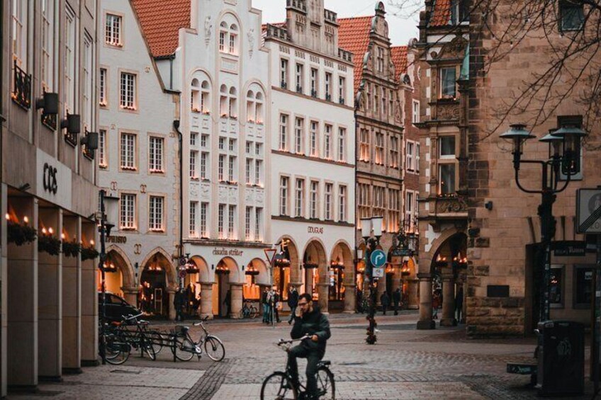 A cobblestone street lined with historic buildings, a cyclist, and a street lamp. 3