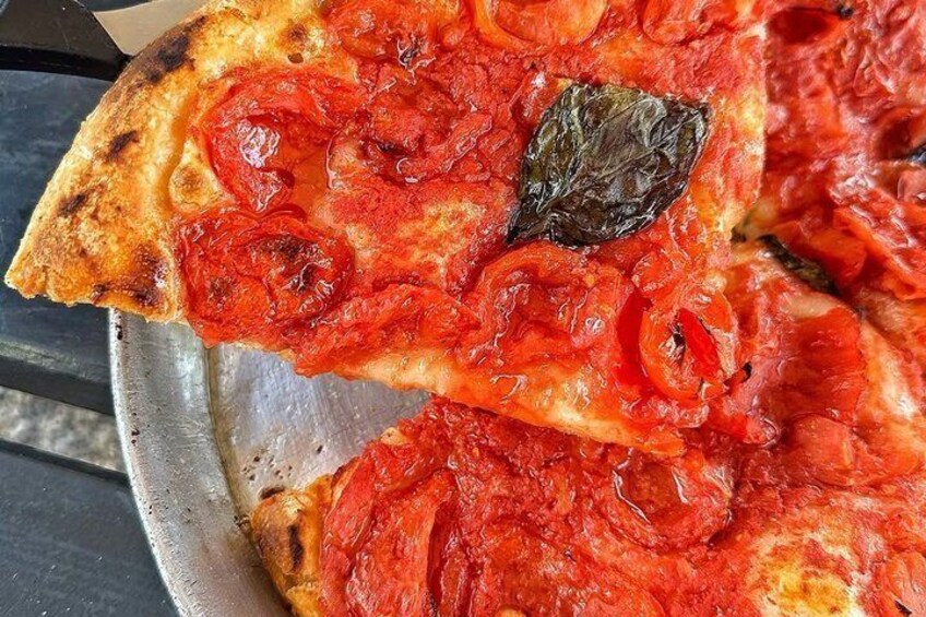 A pizza with tomato sauce and slices of tomato on a metal tray. 2