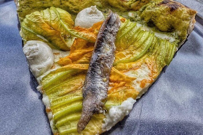 A pizza with green leaves and a fish on top. 3