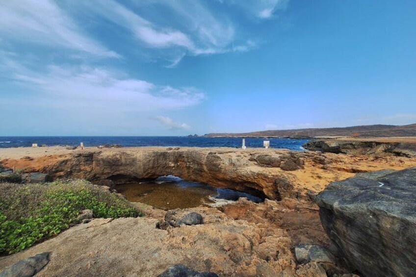 A rocky coastal landscape with a small water body, white structures, and distant hills. 2