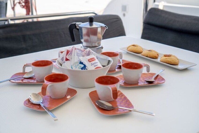 A table with a coffee pot, cups, saucers, and a plate of cookies. 3
