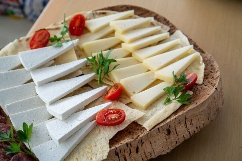A charcuterie board with cheese, tomatoes, and herbs. 5