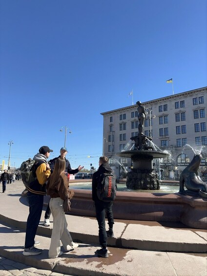 A public square with a fountain, a statue, and a building with flags. 5