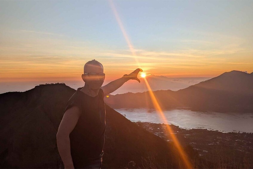 A person standing on a hill with a sunset in the background. 3