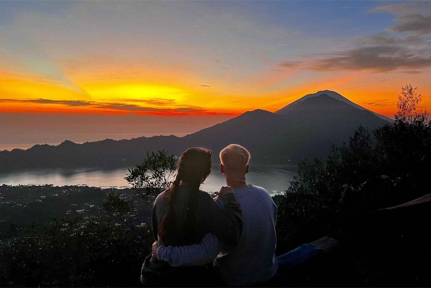 A couple overlooking a sunset with a mountain in the background. 2