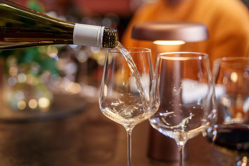 A bottle of wine being poured into a glass. 4