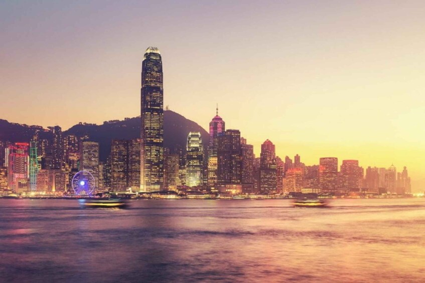 A city skyline at dusk with illuminated buildings and a Ferris wheel. 1
