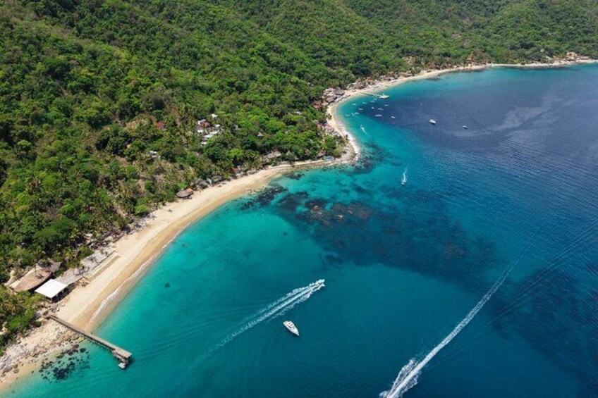 A coastal landscape with a sandy beach, clear turquoise waters, and a pier extending into the sea. 2