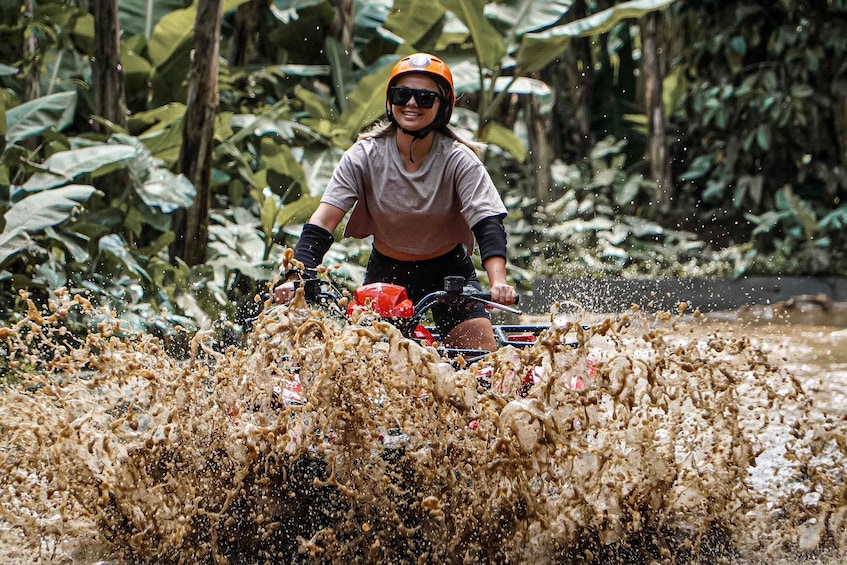 A person riding a motorcycle through a muddy area with splashes of mud around. 5