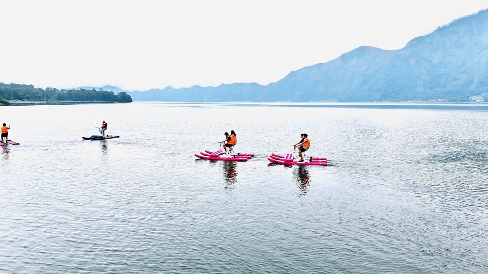 People riding inflatable tubes on a calm lake with mountains in the background. 5