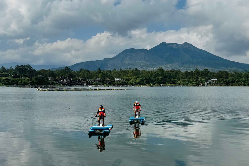 Two people on watercrafts in a calm lake with a mountain in the background. 2