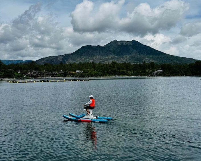 A person riding a blue inflatable raft on a calm lake with a mountain in the background. 4