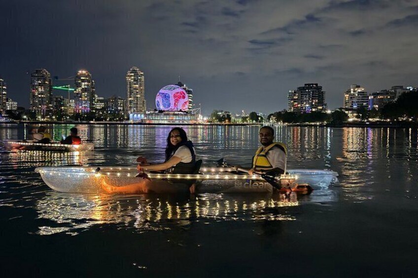Two people in a kayak on a body of water with a city skyline in the background. 4