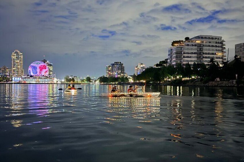 A cityscape with illuminated buildings and a river with boats. 5