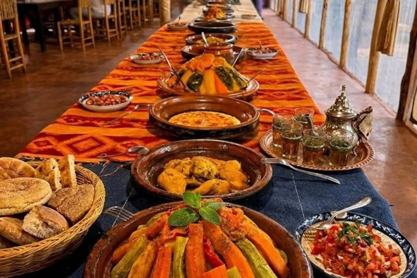 A long dining table with various dishes and drinks, set in a room with wooden chairs. 5