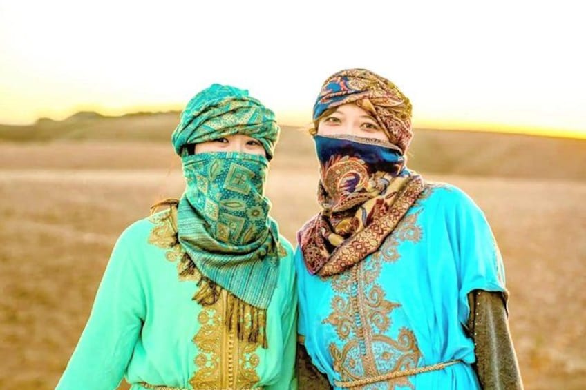 Two individuals in traditional attire standing in a barren landscape with a flat horizon. 3