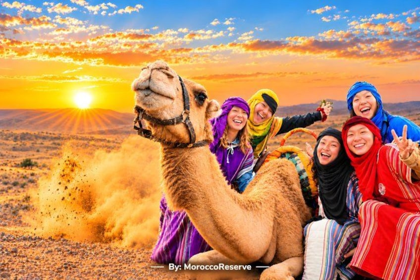 A camel with people around it in a desert landscape during sunset. 1