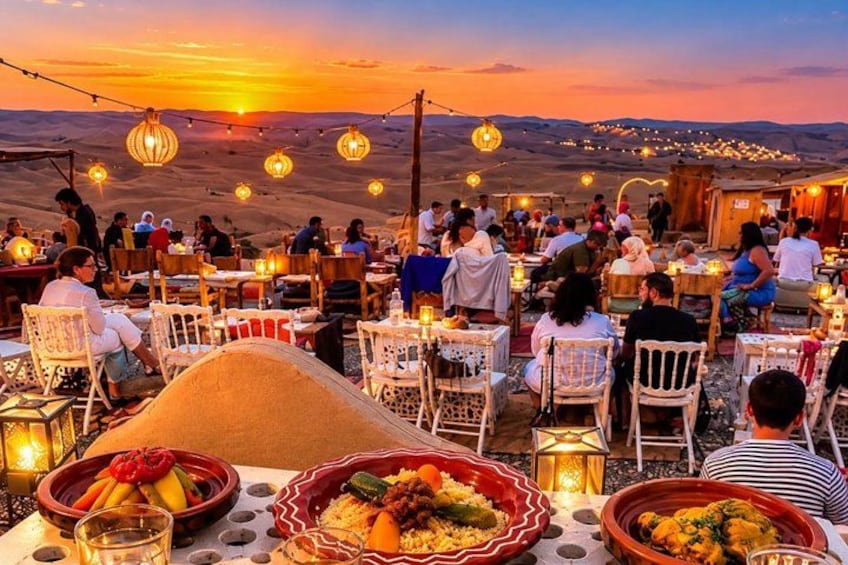A desert dining area with tables and chairs, food, and a sunset in the background. 3