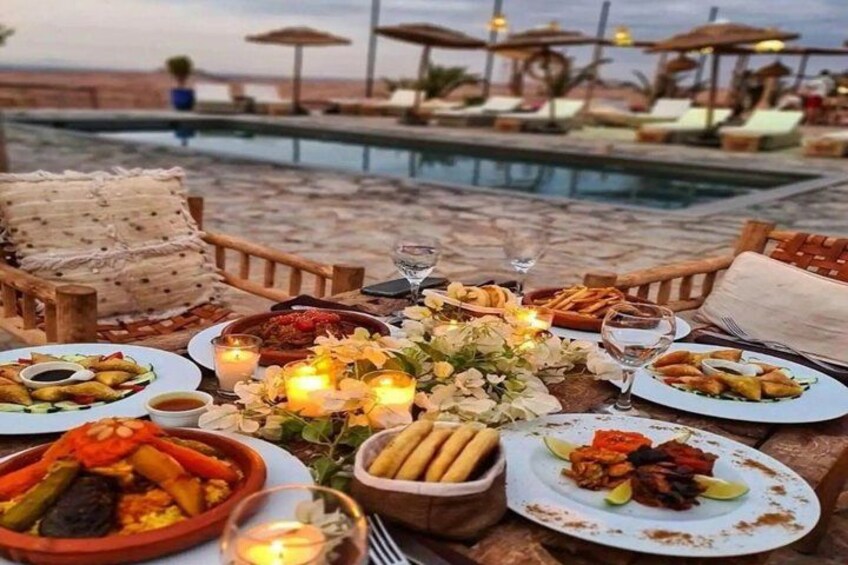 A dining table with various dishes, candles, and a poolside setting. 4