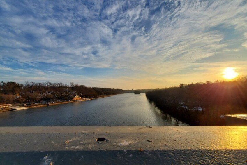 A river with a sunset, a bridge, and a tree line. 2