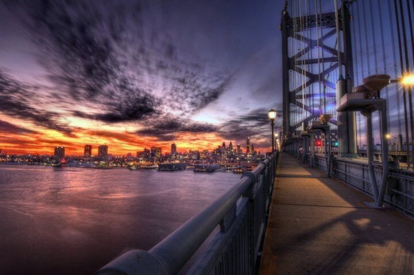 A sunset over a city skyline with a bridge in the foreground. 3