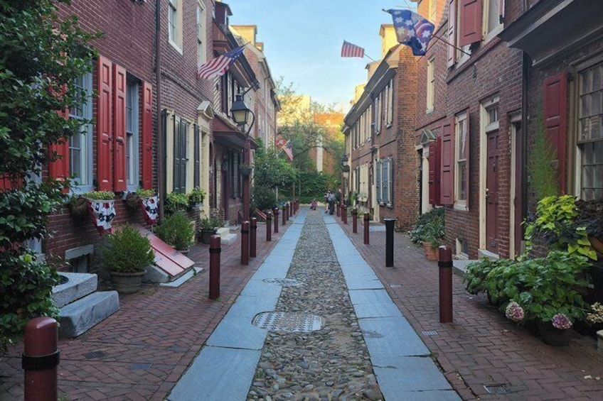 A brick-paved street lined with red-framed buildings, some with American flags. 5