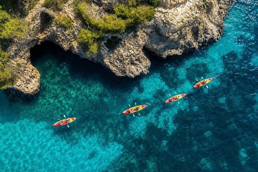 Kayaks on clear turquoise water near rocky cliffs. 1