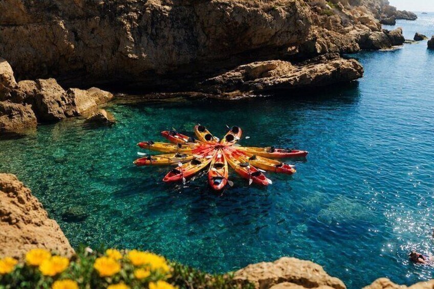 Kayaks arranged in a circle on clear water near rocky cliffs. 4
