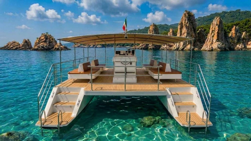 A boat with a covered deck, clear blue water, and rocky cliffs in the background. 3