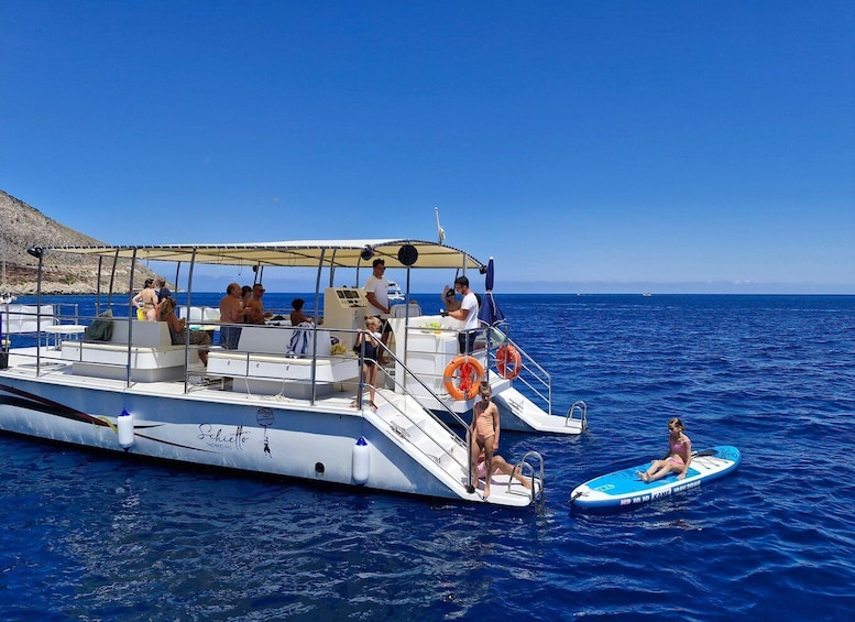A boat with people on board, a lifebuoy, and a person on a paddleboard. 2
