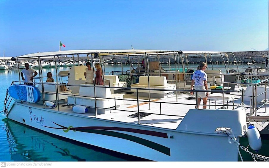 A boat docked at a marina with people on board and a clear sky. 4