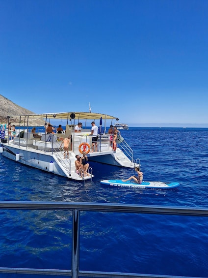 A boat with people on board, a lifebuoy, and a clear blue sea. 1