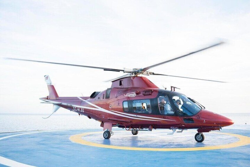 A red helicopter with 'FLYING' written on the side, parked on a blue landing pad. 1