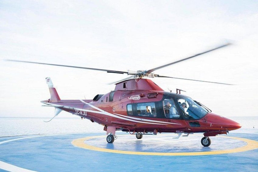 A red helicopter on a helipad with a clear sky in the background. 1