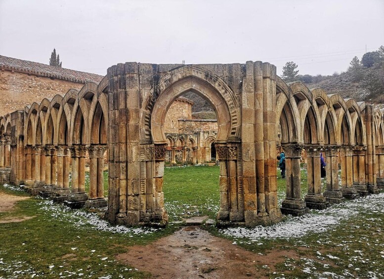 A medieval stone archway with a central archway leading to ruins. 5